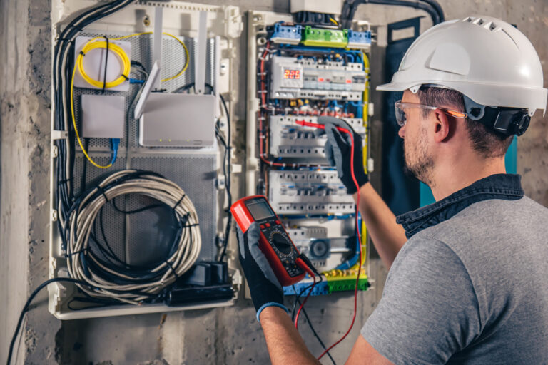 Man, an electrical technician working in a switchboard with fuses